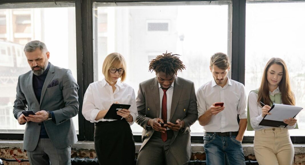 A diverse group of colleagues using mobile devices in an office setting.