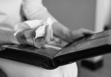 Half of grieving workers handle ‘death admin’ during work hours, study finds Close-up of hands holding a photo album and tissue, evoking memories.