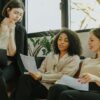 Three professional women engaged in a collaborative meeting in a modern office setting.
