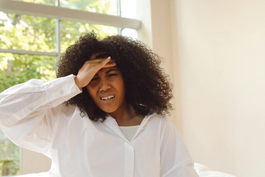 A woman holds her hand to her head as she experiences a hangover.