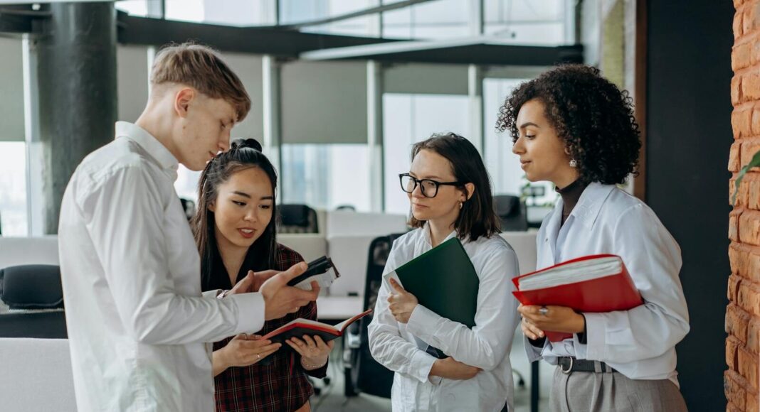 Four young colleagues engage in a collaborative discussion in a modern office setting.