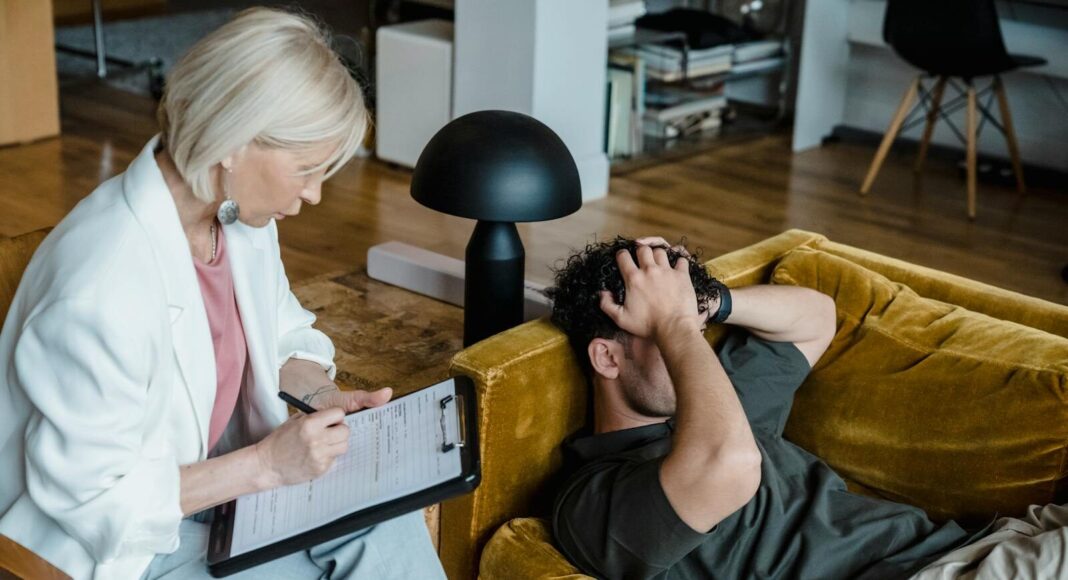 A therapist conducts a session with a client discussing mental health in a cozy office setting.