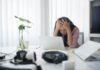 Mental health cited in a third of sickness absence cases ahead of sick pay changes Frustrated woman sitting at desk with laptop, showing stress in a modern office environment.