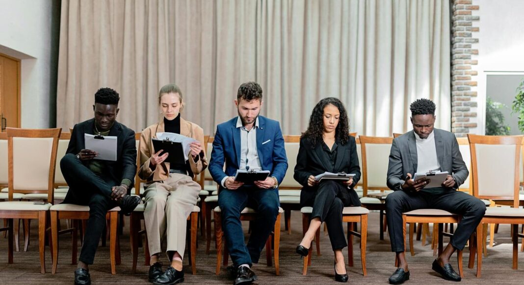 People sitting on chairs waiting to be interviewed for a job.