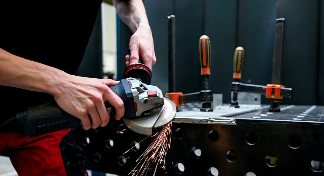 Photo by Mike Winkler A man using a grinder on a piece of metal.