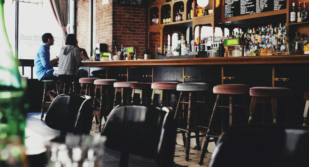 Two people sitting at the bar of a pub.