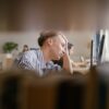 A person appears stressed while working at a computer.