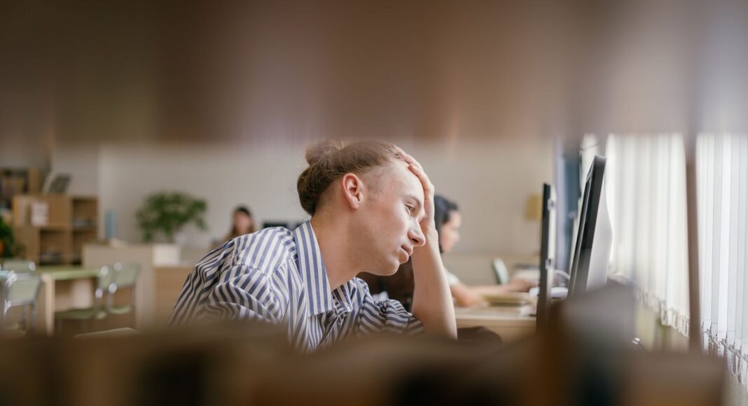 Photo by Mikhail Nilov A person appears stressed while working at a computer.