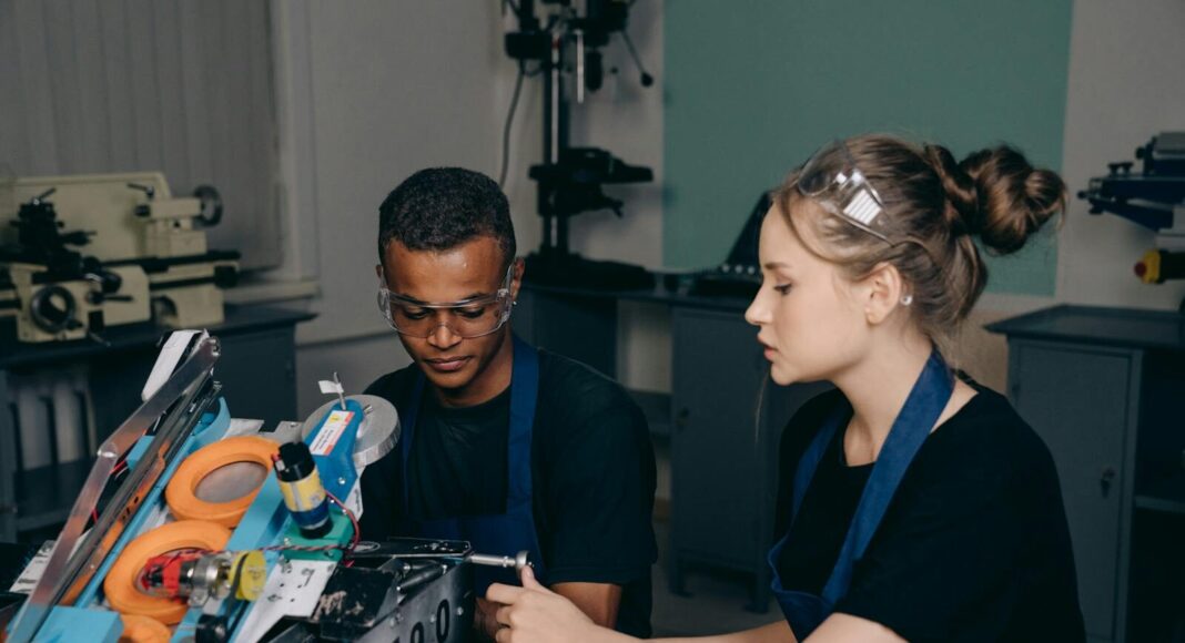 Young engineers working on a robot project in a workshop setting.