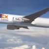 A FedEx Express cargo airplane, staffed by dedicated personnel, is flying in a clear blue sky above the clouds.