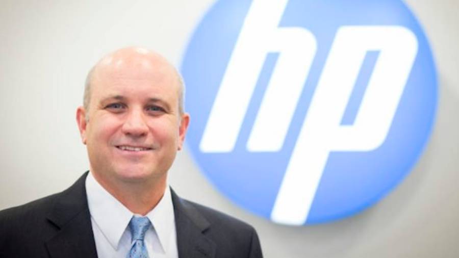 A man in a suit and tie stands in front of a blue circle with the HP logo, embodying the essence of effective People Management and HR expertise.