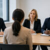 A woman sits before three people during a job interview.