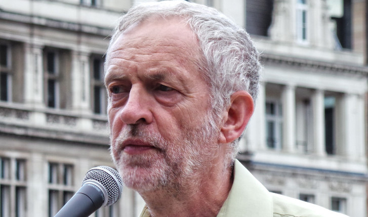 An older man with a beard speaking into a microphone, set against a blurred urban background, discussing HR strategies. An older man with a beard speaking into a microphone, set against a blurred urban background, discussing HR strategies.