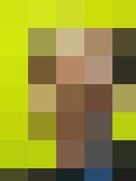 A man in a suit and tie, representing Human Resources, smiling in front of a yellow wall.