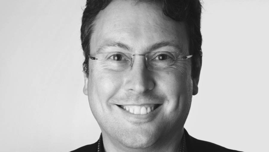 A person with glasses and a dark shirt smiles at the camera in a black and white portrait, encapsulating a moment of genuine warmth perfect for an HR profile.
