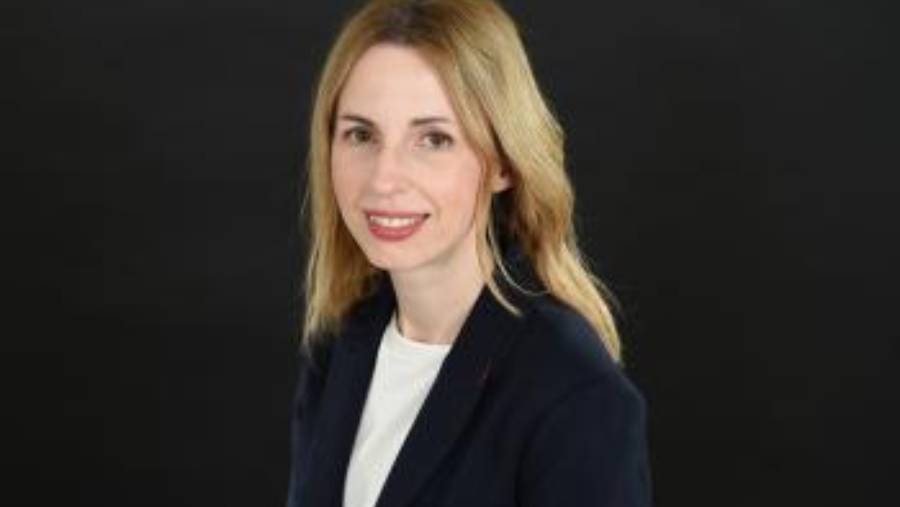 A woman with long, blonde hair and a black blazer smiles against a dark background, embodying confidence as she navigates visa solutions.