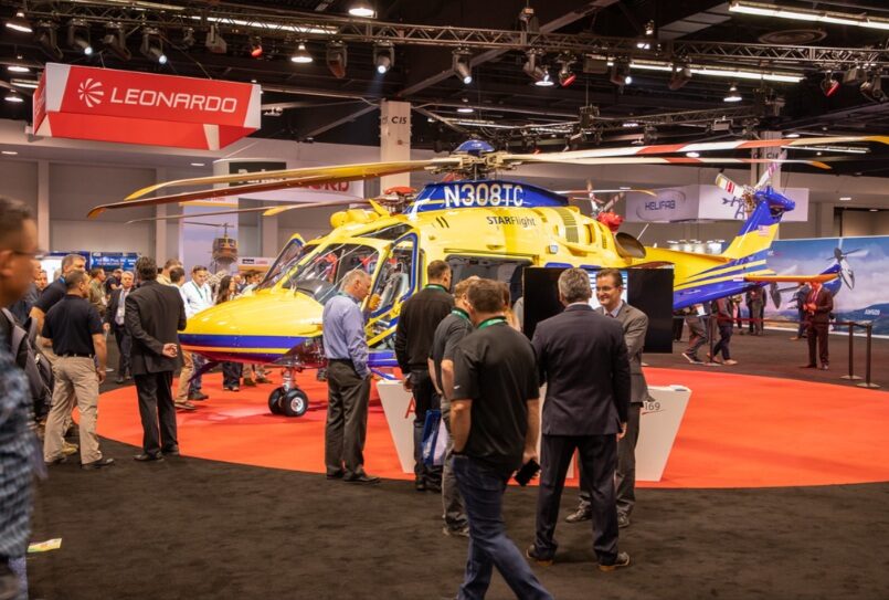 Leonardo People walk around a helicopter at an exhibition attended by Leonardo.