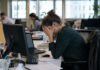 Government launches major overhaul of mental health care with focus on prevention A woman sits at an office desk with her head in her hands.