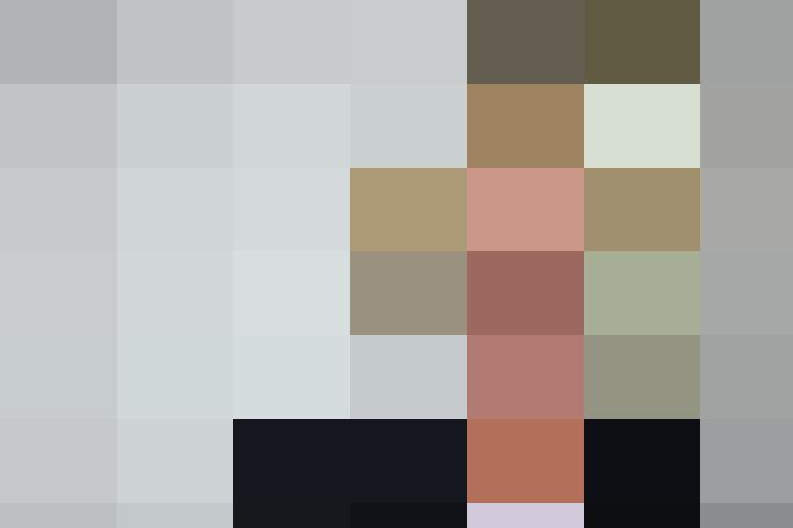 A woman in a business suit is smiling in front of a wall.