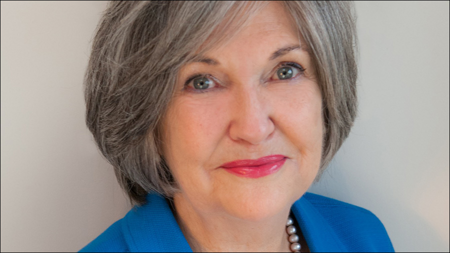 A woman with short gray hair, wearing a blue top and pearl necklace, smiles slightly at the camera against a plain background. Her calm demeanor exudes a sense of expertise in Human Resources.