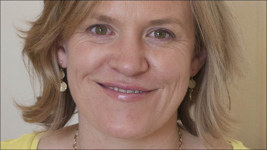 A person with short, blonde hair and light-colored eyes is smiling. They are wearing drop earrings and a necklace, giving off a professional appearance suitable for an HR personnel profile. The background is neutral.