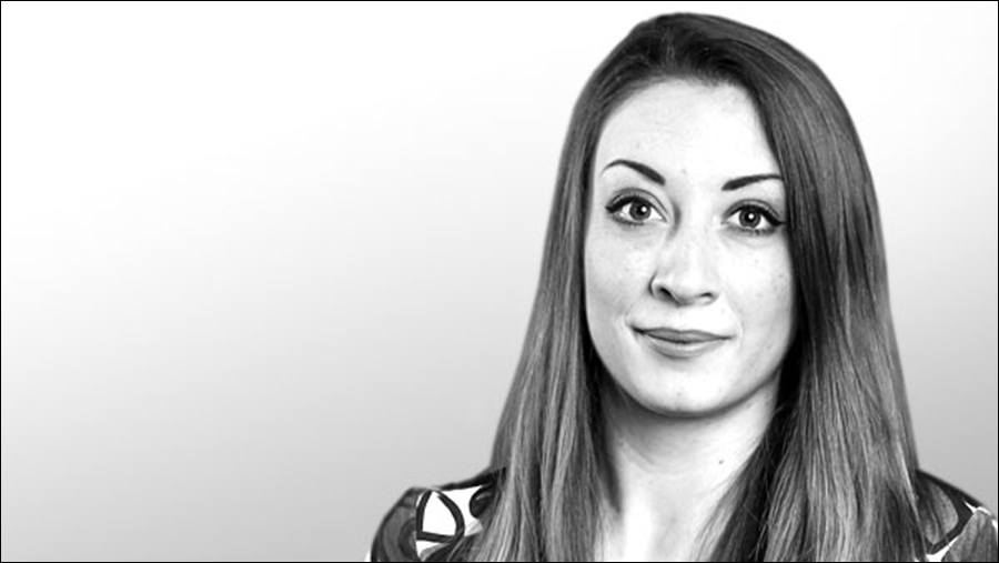 Black-and-white portrait of a woman with long straight hair, wearing a patterned top, looking toward the camera with a neutral expression, resembling a poised professional in Human Resources.