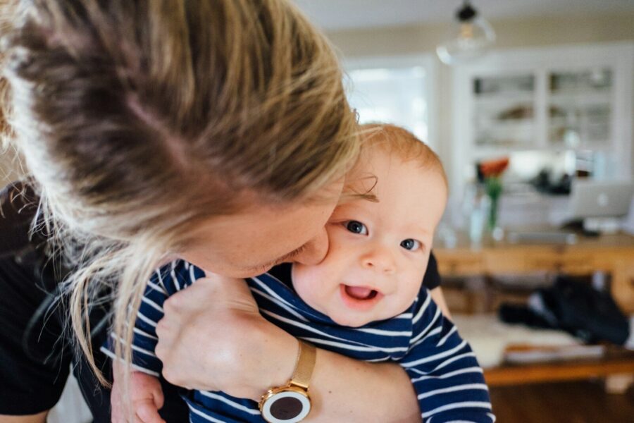 A mother hugging and kissing her infant.