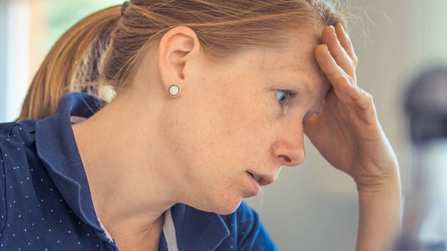 A person with a ponytail and earrings rests their head on their hand, appearing stressed or tired, possibly after a long day in Human Resources.