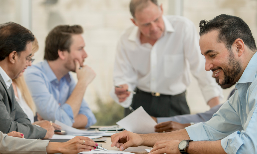 four men in a boardroom talking