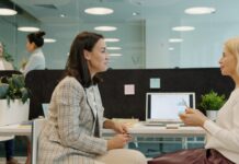 ‘One in three employees reluctant to speak up’ as wellbeing gaps widen Two women talking at a desk in an office.