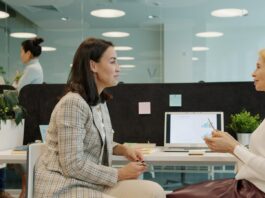 ‘One in three employees reluctant to speak up’ as wellbeing gaps widen Two women talking at a desk in an office.