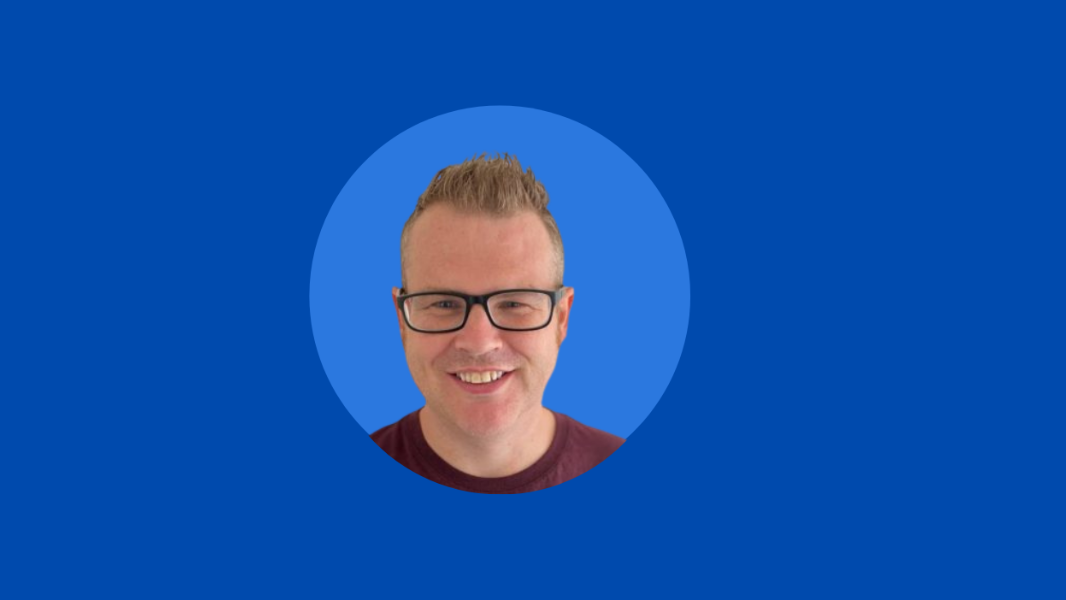 A person with short hair and glasses is smiling, centered in a circular frame with a blue background, embodying the joy of remote working.