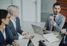 Not posh enough? ‘Accent anxiety’ holding workers back Four professionals in a business meeting around a table.