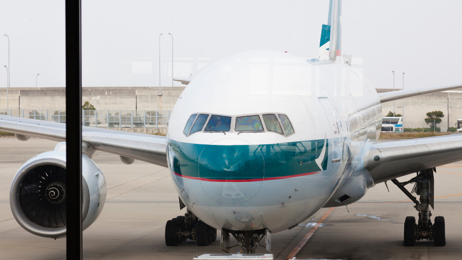 Front view of a large passenger airplane with teal and white livery parked at an airport gate, its pilots preparing for the next journey.
