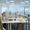 Staff take part in a learning session, seated at desks while an instructor talks at a board in front.
