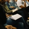 People taking part in a training session, seated and with books open on their laps.