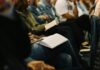 Inefficient staff training ‘costs UK businesses £416m a year’ People taking part in a training session, seated and with books open on their laps.