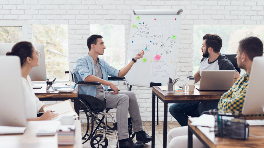 man in wheelchair presenting to colleagues