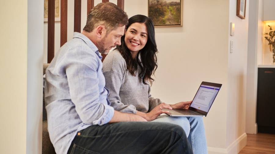 Man and woman sitting on stairs, smiling at each other, while the man uses a laptop to review HR policies.