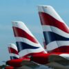 Tails of British Airways planes lined up at an airport.