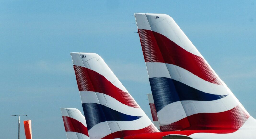 Tails of British Airways planes lined up at an airport.