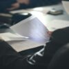 A person reads paper documents at a desk.