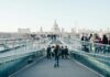 Vacancies fall to lowest level in five years as employers delay recruitment People walking across a bridge in London.