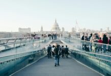 Vacancies fall to lowest level in five years as employers delay recruitment People walking across a bridge in London.