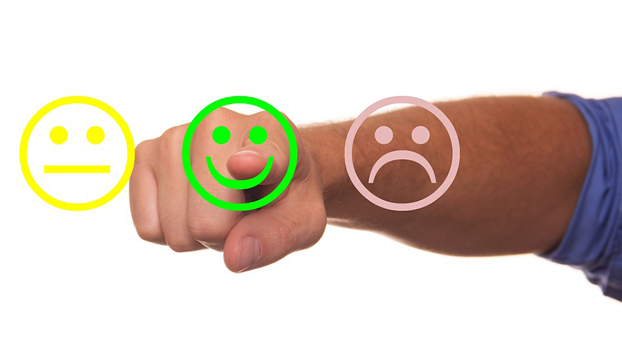 A hand gestures towards a green smiling face among three emoticons: a yellow neutral face, a green smiling face, and a red sad face, reflecting effective People Management in HR.
