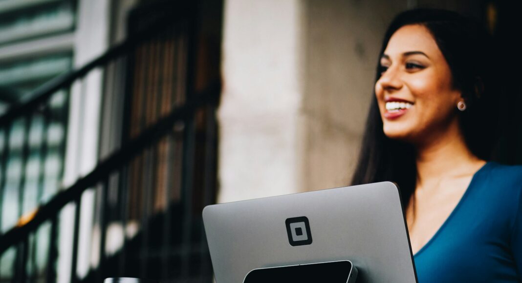 A woman smiles while working at a computer.