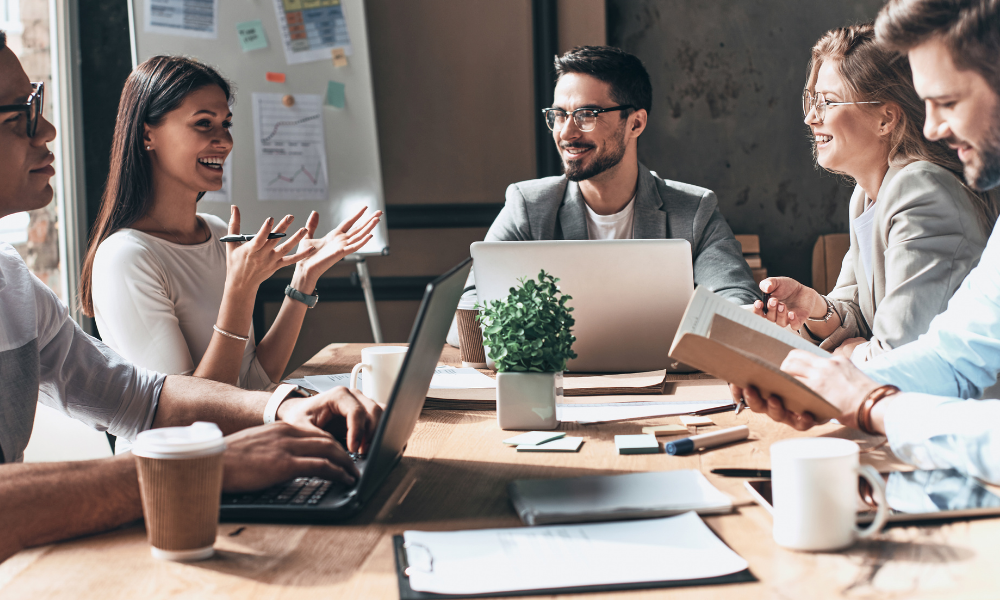 people at work with laptops, all laughing