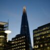 The Shard towers above other London office buildings at dusk.