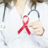 A doctor wearing holding a red cancer ribbon.