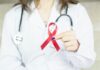Cancer, mental health and musculoskeletal disorders account for ‘half of employee health referrals’ A doctor wearing holding a red cancer ribbon.